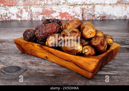 Eine Gruppe von reifen, weichen und klebrigen medjool- und Zamli-Datteln in einem Serviergericht aus Olivenholz Stockfoto