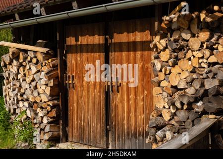 Gemütliche kleine Scheune mit einem Haufen Brennholz in den Alpen verloren. Foto aus Füssen, Bayern, 2019 Stockfoto