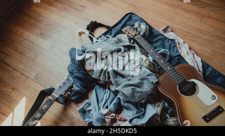 Gitarre ruht auf einem Stapel blauer Jeans und Jacken Stockfoto