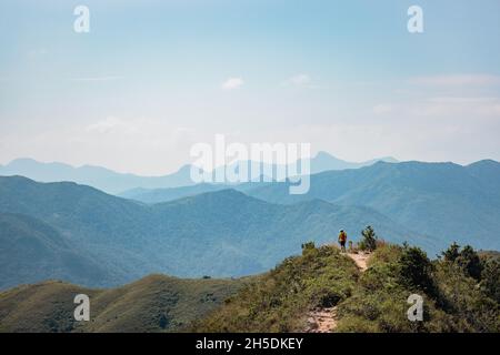 Erstaunliche Ansicht des Mannes, der auf dem Fußweg auf dem Berg, in der Nähe des Sharp Peak, Sai Kung, Hongkong, spricht Stockfoto