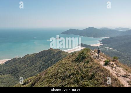 Erstaunliche Ansicht des Mannes, der auf dem Fußweg auf dem Berg, in der Nähe des Sharp Peak, Sai Kung, Hongkong, spricht Stockfoto