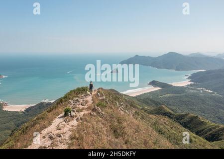 Erstaunliche Ansicht des Mannes, der auf dem Fußweg auf dem Berg, in der Nähe des Sharp Peak, Sai Kung, Hongkong, spricht Stockfoto