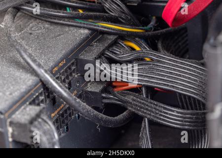 Schwarze interne Stromkabel und Anschlüsse des PCs, die mit Staub, Fell und Haaren bedeckt sind Stockfoto