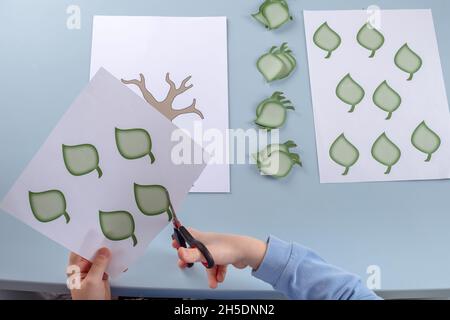 Das Kind schneidet die Blätter aus, um einen Stammbaum zu erstellen. Hochwertige Fotos Stockfoto