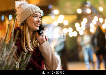 Einkaufen weihnachten Reisen Menschen Konzept. Glückliche Frau mit Einkaufstasche mit digitalem Gerät im Freien Stockfoto