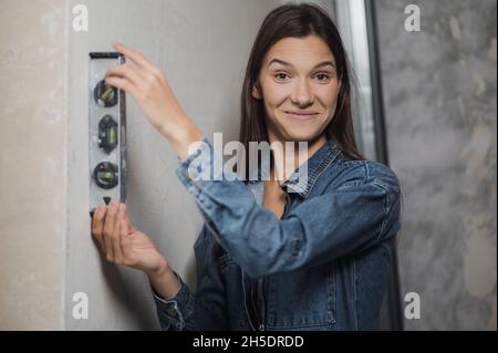 Die Frau verwendete ein Gleichgewichtslineal. Messung der vertikalen Abweichung der Konstruktion. Nahaufnahme des Blasenlineals Stockfoto