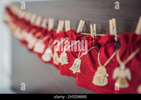 Adventskalender Rote Tüten an einem Seil hängen auf einem Kinderbett Stockfoto