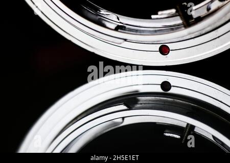 Makroaufnahme des roten Punkts eines Objektivadapters aus Metall mit Vintage-Kamera auf eine digitale Spiegelreflexkamera. Stockfoto