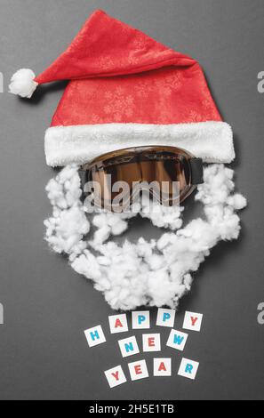 Roter Samthut mit Schneemaske und wattem Schnurrbart und Bart und mit der Aufschrift Frohes neues Jahr. Das lustige Gesicht des Weihnachtsmanns Stockfoto