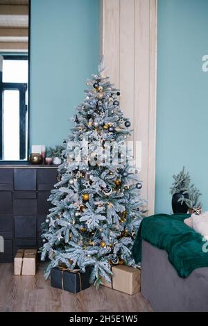 Stilvoller silberner Weihnachtsbaum mit goldenem Spielzeug im Wohnzimmer in blauen Minztönen Stockfoto