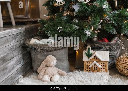 Weihnachtsdekor im Kinderzimmer: Weicher Spielzeughase, Spielzeughaus unter dem Baum Stockfoto