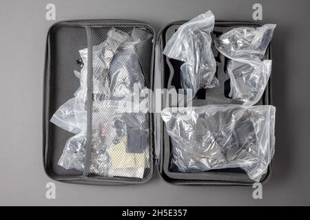 Ein offener grauer Koffer, in dem sich die Dinge in Paketen befinden. Kameraausrüstung Stockfoto