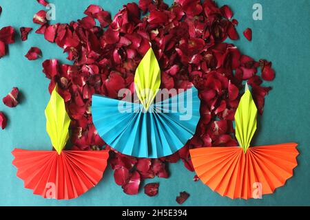 Bunte Diwali-Lampen mit Origami-Papier und frischen Rosenblüten auf blauem Hintergrund Stockfoto