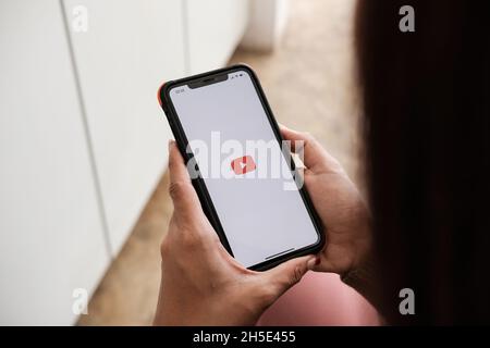 CHIANG MAI, THAILAND - 7. NOV 2021: Frau mit iphone x und Youtube-Apps auf dem Bildschirm. YouTube ist die beliebte Online-Website zum Teilen von Videos Stockfoto