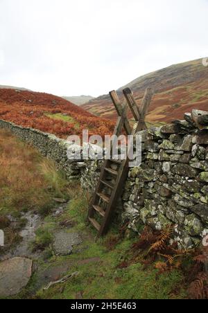 Leiter über einer Trockensteinmauer im Lake District National Park, Cumbria, England, Großbritannien. Stockfoto