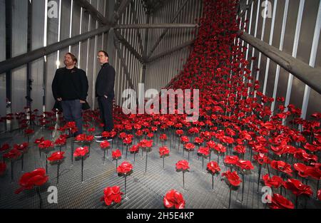 Der Künstler Paul Cummins (links) und der Designer Tom Piper stehen neben „Poppies: Wave and Weeping Window“, einem neuen Kunstwerk aus tausenden handgefertigten Keramikmohn, der 30 Meter tief im Air Shard im IWM North in Manchester zusammenfließt. Die Mohnskulpturen waren ursprünglich Teil von 'Blood Sweeped Lands and Seas of Red' im Tower of London im Jahr 2014 und später von 'Poppies: Wave and Weeping Window', das zwischen 2014 und 2018 durch Großbritannien tourte. Bilddatum: Dienstag, 9. November 2021. Stockfoto