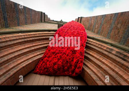 Cradley, West Midlands, Großbritannien. November 2021. Eine 75 Meter lange Kaskade aus gestrickten Mohnblumen schmückt den Turm der Pfarrkirche St. Peter in Cradley, West Midlands, vor dem Gedenktag. Tausende von handgestrickten Mohnblumen wurden von Einheimischen und von ausländischen Mitwirkenden kreiert und von Doreen Clifton, einer ortsansässigen Frau, ins Leben gerufen. Kredit: Peter Lopeman/Alamy Live Nachrichten Stockfoto