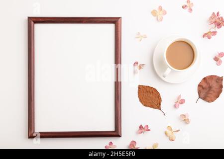Komposition mit Holzrahmen, braunen Buchen Herbstblättern, Hortensien Blumen und Tasse Kaffee. Mockup auf weißem Hintergrund. Leer, flach liegend, Draufsicht, Stockfoto