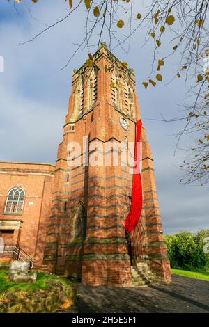 Cradley, West Midlands, Großbritannien. November 2021. Eine 75 Meter lange Kaskade aus gestrickten Mohnblumen schmückt den Turm der Pfarrkirche St. Peter in Cradley, West Midlands, vor dem Gedenktag. Tausende von handgestrickten Mohnblumen wurden von Einheimischen und von ausländischen Mitwirkenden kreiert und von Doreen Clifton, einer ortsansässigen Frau, ins Leben gerufen. Kredit: Peter Lopeman/Alamy Live Nachrichten Stockfoto