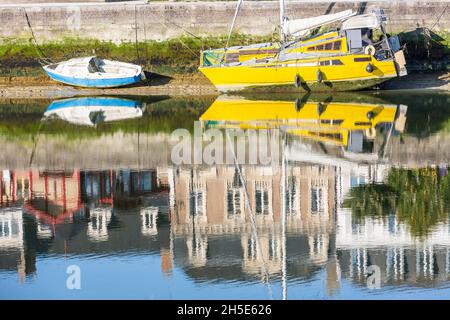 Kleine Fischerboote, die bei Ebbe vor Anker liegen. Spiegelungen von Häusern, die am Kai gebaut wurden. Saint-Valery, Somme-Bucht, Frankreich Stockfoto