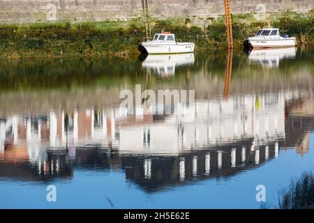 Kleine Fischerboote, die bei Ebbe vor Anker liegen. Spiegelungen von Häusern, die am Kai gebaut wurden. Saint-Valery, Somme-Bucht, Frankreich Stockfoto