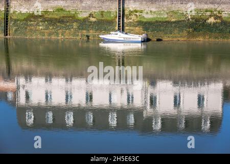 Kleine Fischerboote, die bei Ebbe vor Anker liegen. Spiegelungen von Häusern, die am Kai gebaut wurden. Saint-Valery, Somme-Bucht, Frankreich Stockfoto