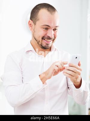 Positiver junger Mann mit Smartphone Stockfoto