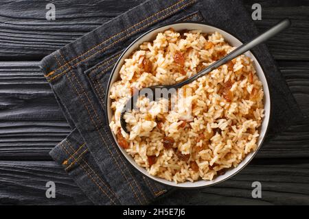 Kokosnusspilaf-Reis mit Rosinen aus der Nähe in einer Schüssel auf dem Tisch. Horizontale Draufsicht von oben Stockfoto