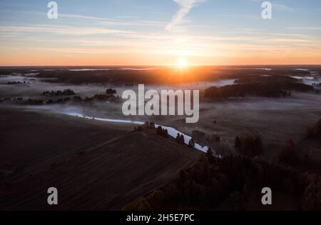 Sonnenaufgang über der ländlichen Landschaft mit Nebel und Fluss.Luftaufnahme einer schönen Morgendämmerung in Finnland. Stockfoto