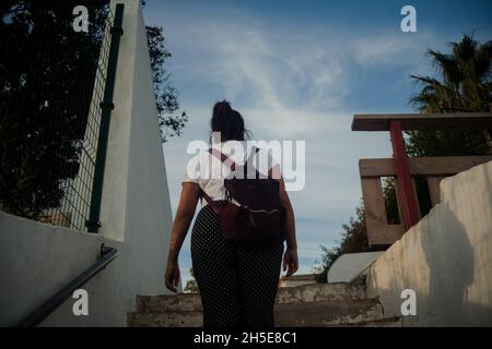 Hispanische Touristin mit Rucksack, die die Treppe hoch läuft Stockfoto