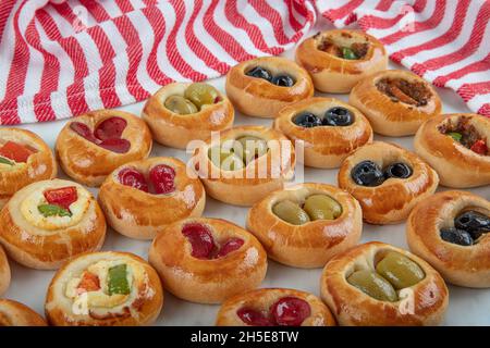 Mini Hot Dogs werden als offenes Buffet serviert. Mini-Pizzas mit Gemüse, Mozzarella-Käse und frischem Basilikum auf Marmorboden, Nahaufnahme, Draufsicht. Stockfoto