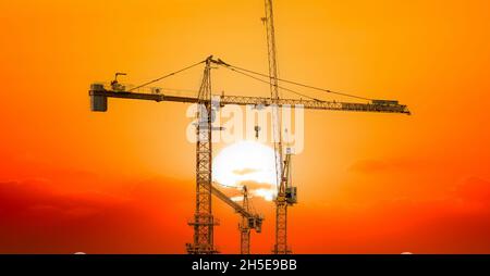Baustelle mit Sonnenaufgang oder Sonnenuntergang und vielen Turmdrehkranen. Stockfoto