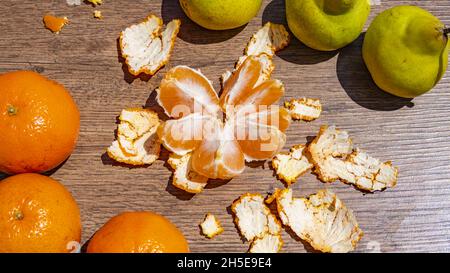 Nahaufnahme einer geschälten Mandarine und Birnen auf einem Holztisch Stockfoto