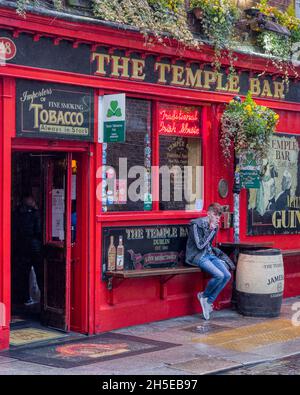 Ein junger Mann raucht vor Dublins berühmtem Temple Bar Pub eine Zigarette Stockfoto