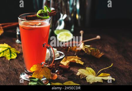 Heißer gebutterter Rum, winterlicher Cocktail mit Apfelsaft, dunklem Rum, Honig, Zimt im Glas auf Holzgrund Stockfoto