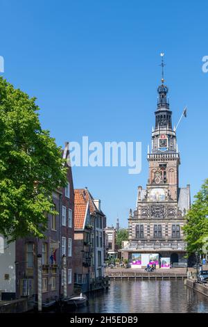 Alkmaar, Niederlande-Juni 2021: Blick über den Kanal auf das historische De Waag (Wägegebäude), das für seinen Käsemarkt berühmt ist, gegen eine klare blu Stockfoto