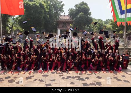 Studenten werfen ihre Mörsertafeln in die Luft, um ihren Abschluss im Dritten Hof, dem Literaturtempel, Hanoi, Vietnam, zu feiern Stockfoto