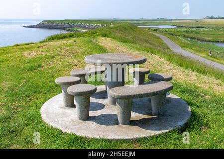Panoramablick über den Deich bei Oosterend auf der niederländischen Insel Texel mit Küstenlinie, Feuchtgebieten und im Vordergrund auf dem Deich ein Beton Stockfoto