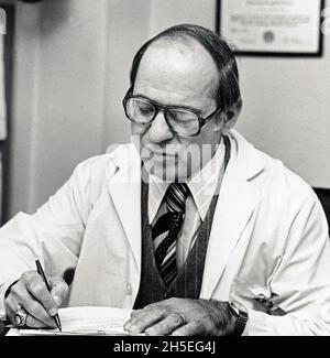 Der Sportmediziner Jets-Teamarzt und Orthopäde Dr. James A. Nicholy schreibt Notizen in seinem Büro am Lenox Hill in Manhattan. Ca. 1976. Stockfoto