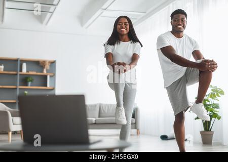 Junge schwarze Paar tun hohe Knie Übung mit pc Stockfoto