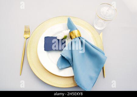 Eleganter und schicker Hochzeitstisch in Gold- und Blautönen und frischen Blumen. Weicher, selektiver Fokus. Stockfoto