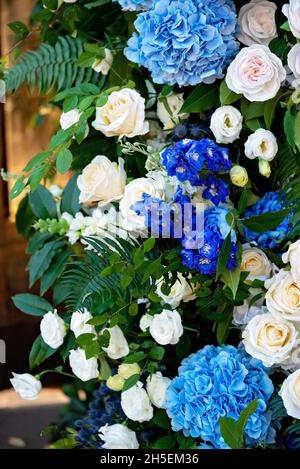 Elemente der Hochzeitsdekoration, dekoriert mit frischen weißen Rosen, blauen Orchideen und Kerzen. Hochzeitsbogen. Weicher, selektiver Fokus. Stockfoto