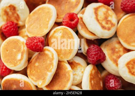 Köstliche frisch gekochte hausgemachte Mini Pfannkuchen mit Himbeeren. Trendiges Essen. Aussicht von oben. Frühstück für Kinder. Stockfoto