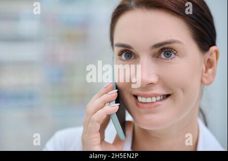 Nahaufnahme einer fröhlichen Frau mit Smartphone in der Nähe des Ohrs Stockfoto