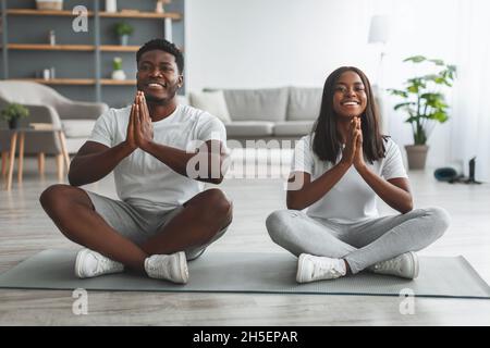 Schwarzes Paar meditiert und hält die Hände in Gebetshaltung zusammen Stockfoto