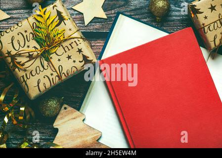 Frohe Weihnachten. Draufsicht auf Bücher, Weihnachtsgeschenke und Weihnachtsdekorationen auf Holztisch. Weihnachten Konzept Hintergrund Stockfoto