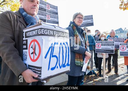 Stuttgart, Deutschland. November 2021. Vertreter von Bürgerinitiativen gegen Fluglärm demonstrieren im Schlossgarten vor dem landtag mit Transparenten gegen Fluglärm, der in ihren Gemeinden durch eine Änderung der Start- und Landestrecke entstehen würde. Links steht der Sprecher der Bürgerinitiativen, Rolf Keck, der der staatlichen lärmschutzbeauftragten Elke Zimmer (MM) eine Unterschriftenbox übergibt. Mehr als 15000 Menschen haben eine Petition gegen die Änderung der Flugroute unterzeichnet. Quelle: Bernd Weißbrod/dpa/Alamy Live News Stockfoto