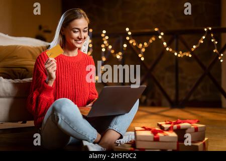 Weihnachtsgeschäfte. Lächelnde Dame mit Laptop und Kreditkarte Stockfoto