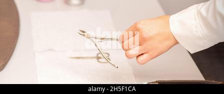 Nagel Zangen in der Hand der weiblichen Maniküre Meister setzen auf das Handtuch vor Nagelpflege in Maniküre Salon Stockfoto