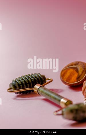 Jade-Scruber-Massagegerät und Rollergesichtsmassager auf rosa Hintergrund. Stockfoto